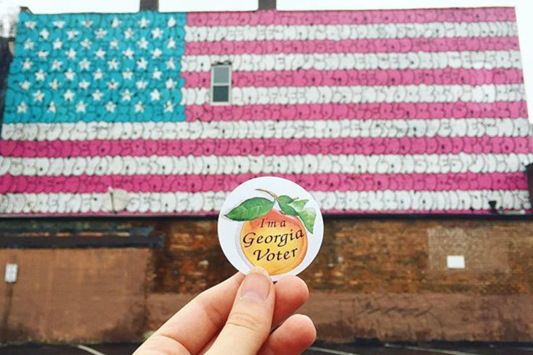 Georgia voter sticker in front of American flag mural