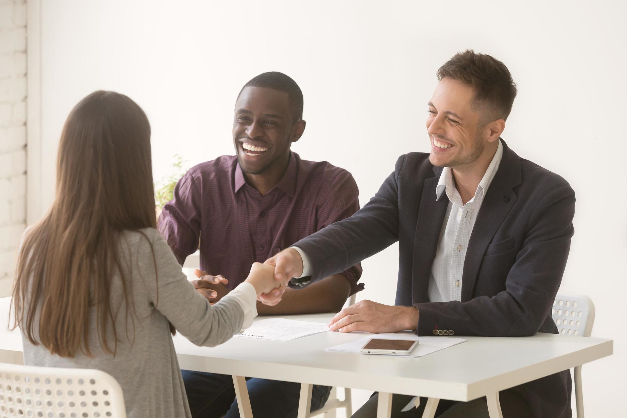 Business woman shaking hand of man across table